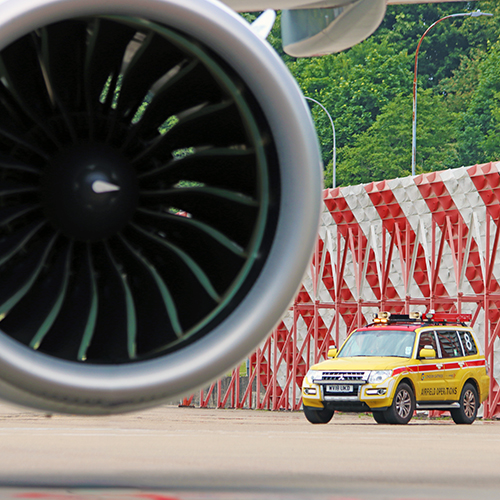 a photograph of a plane engine, with a yellow London Gatwick airfield jeep in the background