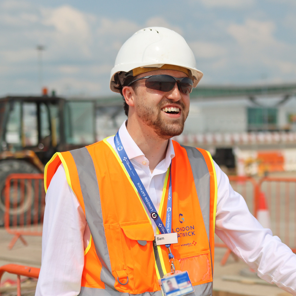 a photograph of Sam Hayter, a London Gatwick field engineer, wearing a high visibility vest on an airfield construction site.