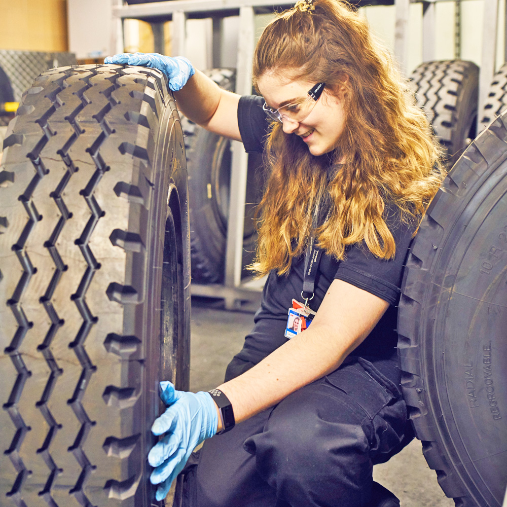 A young female engineer inspecting a huge tyre for the airport shuttle