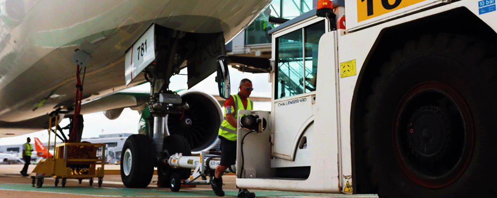a photo of a pushback tractor being attached to the front landing gear of a plane